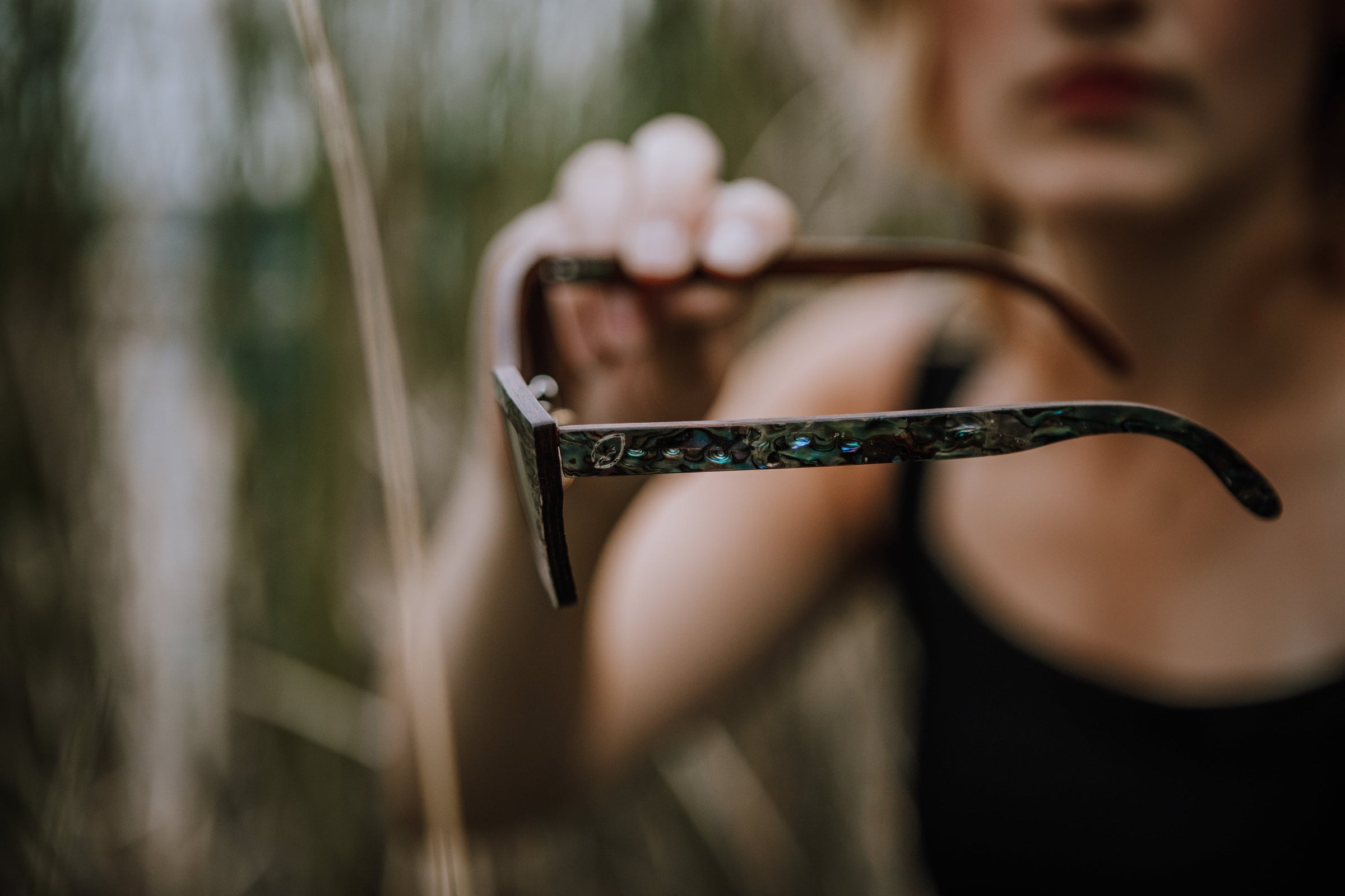 woman holding side view of seashell abalone sunglasses