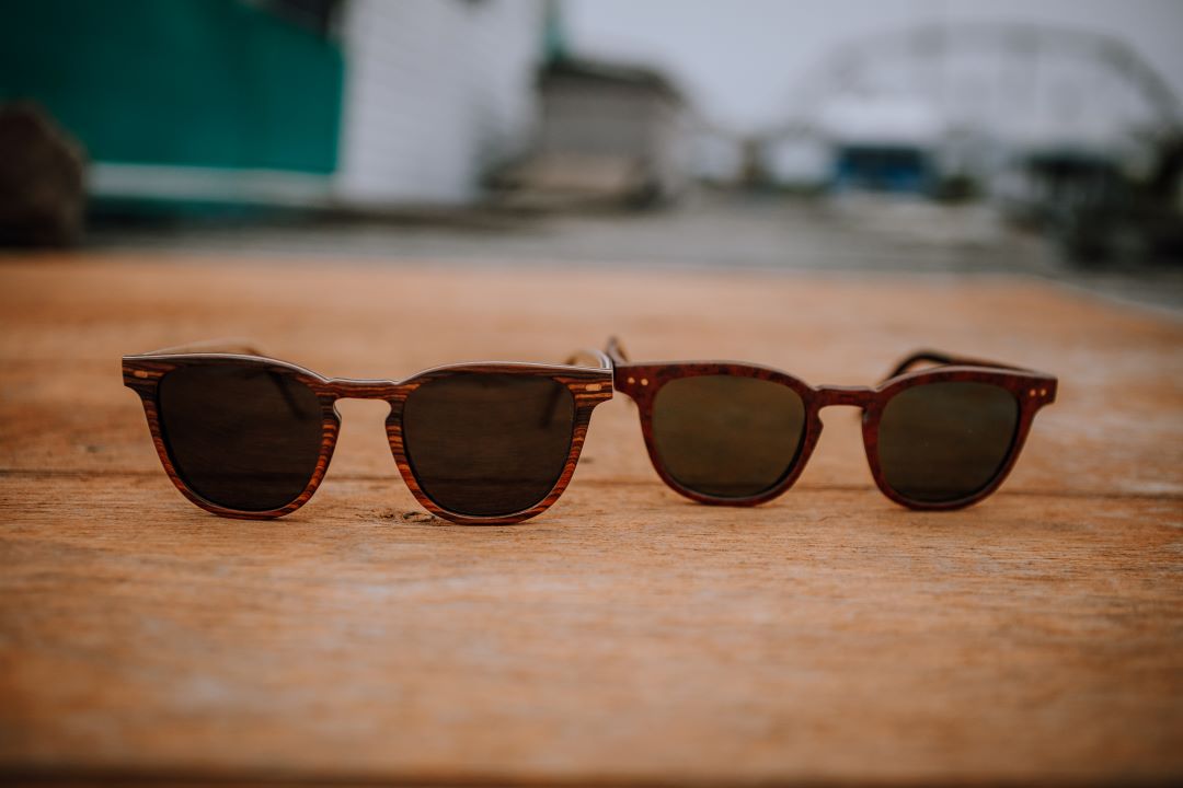 2 sunglasses sitting on wood deck.