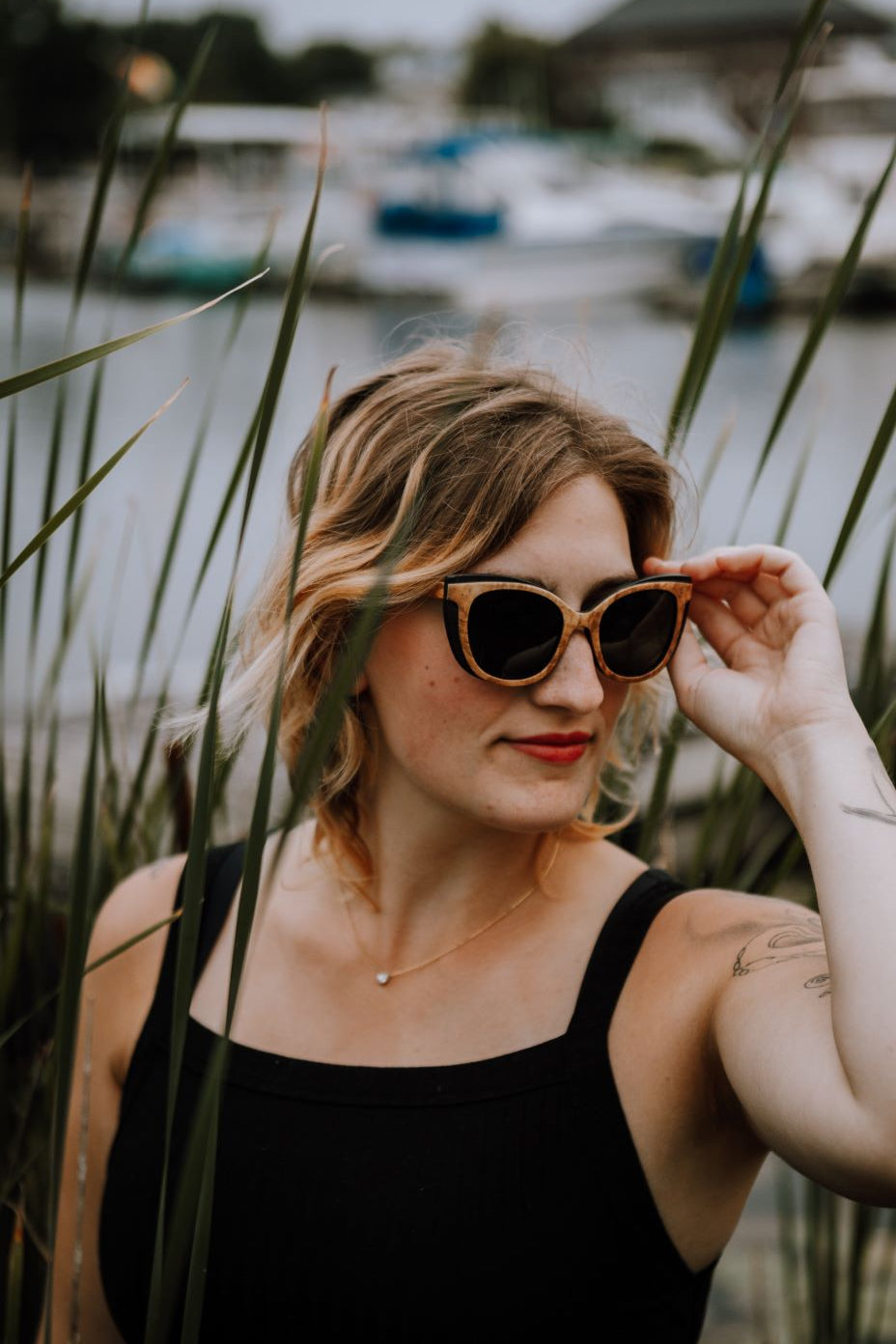 woman in reeds, wearing wood sunglasses