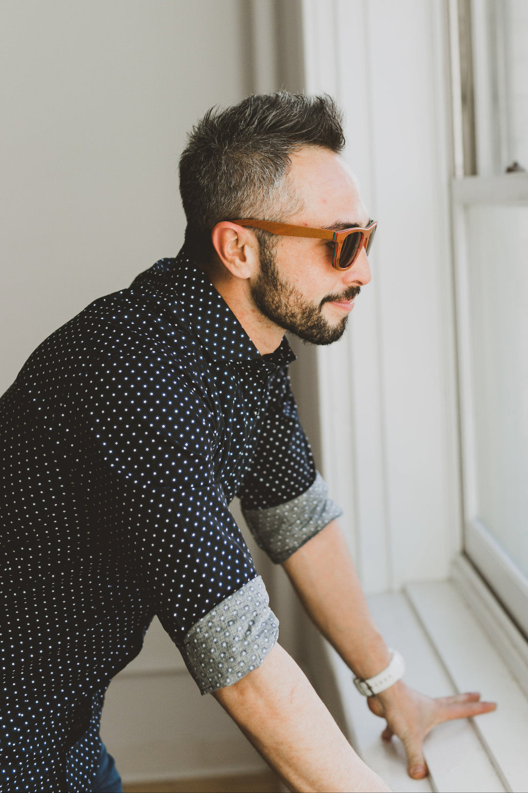 man looking out window, wearing walnut wood sunglasses.