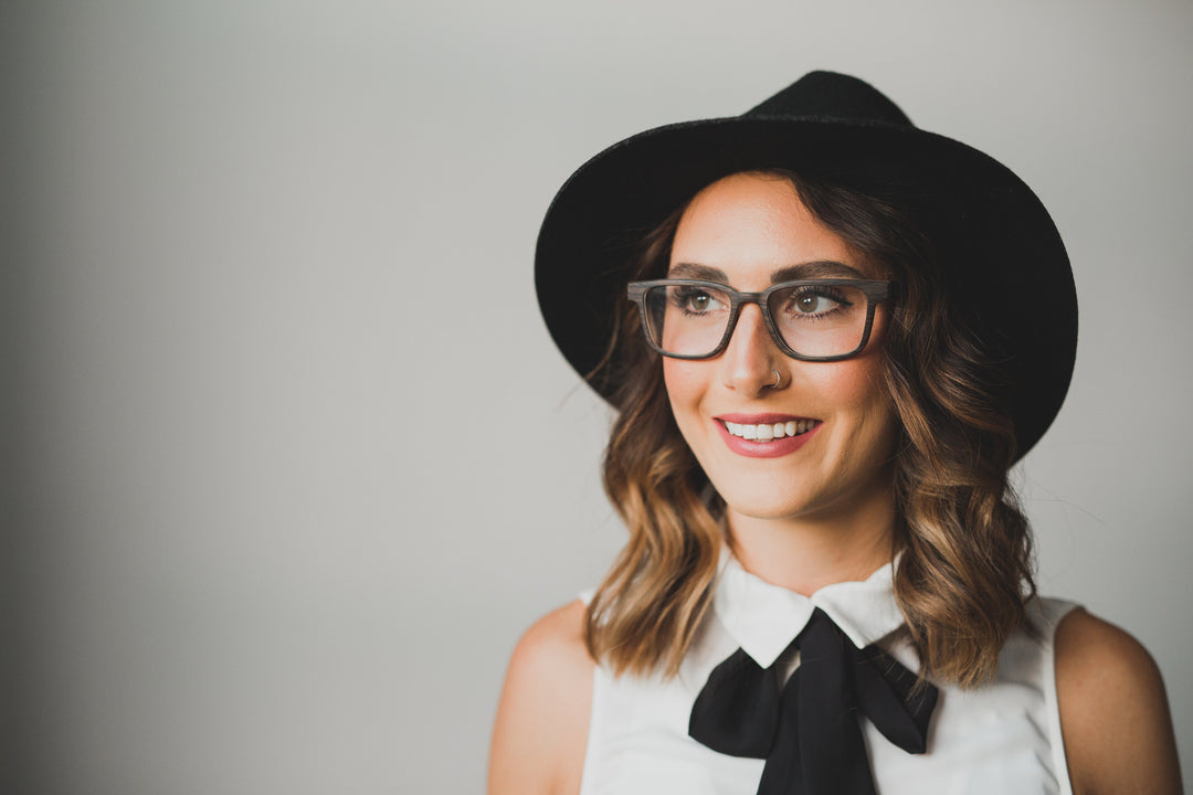 woman with back hat, wearing black oak glasses.