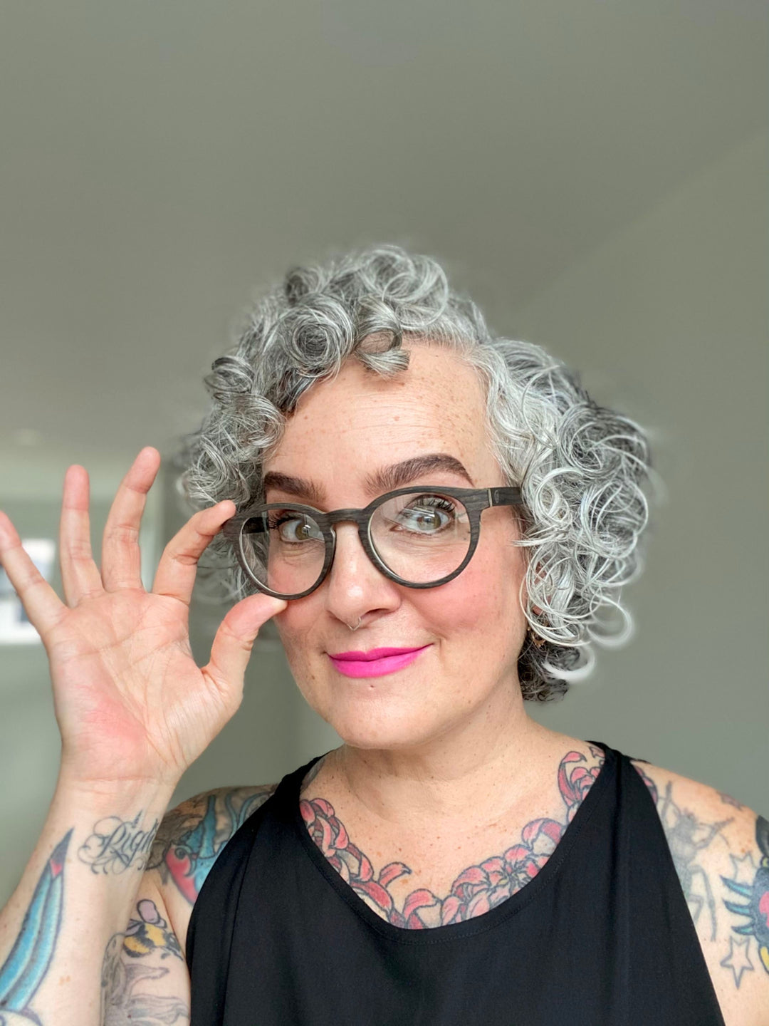 curly haired woman wearing black oak glasses.