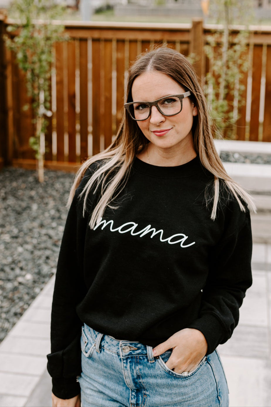 Woman with hand in pocket, wearing black oak wood glasses.