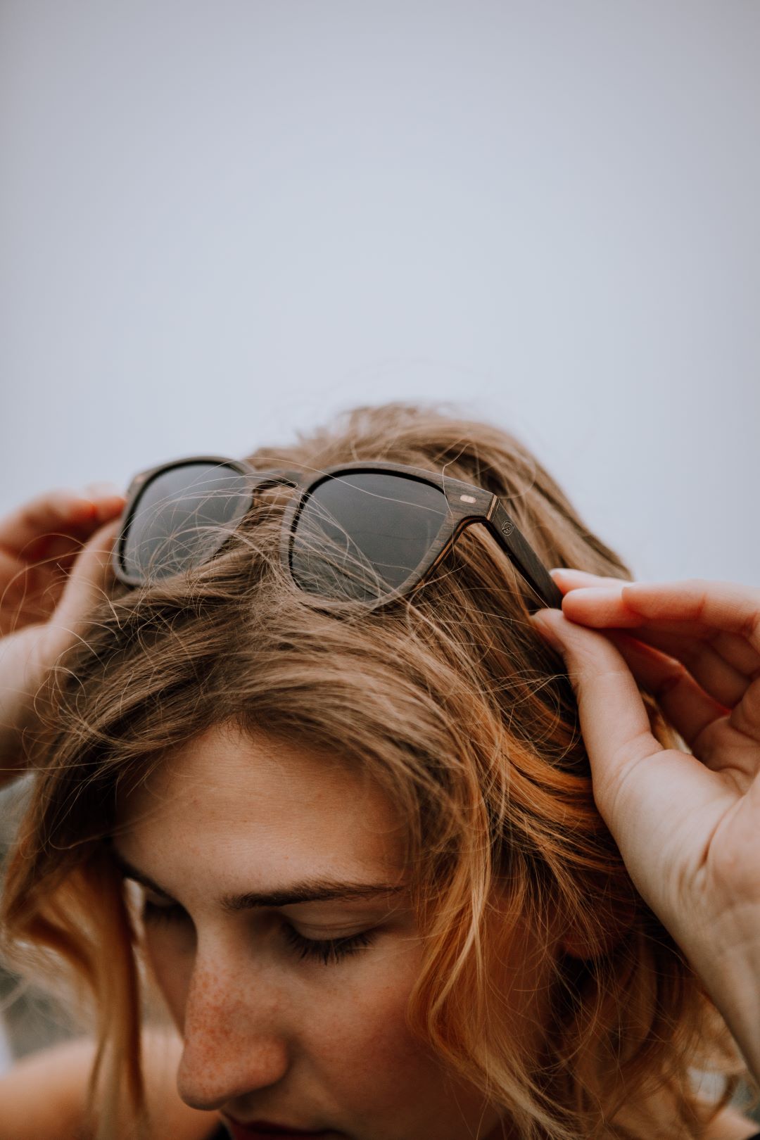 woman wearing black oak wood sunglasses on top of her head. 