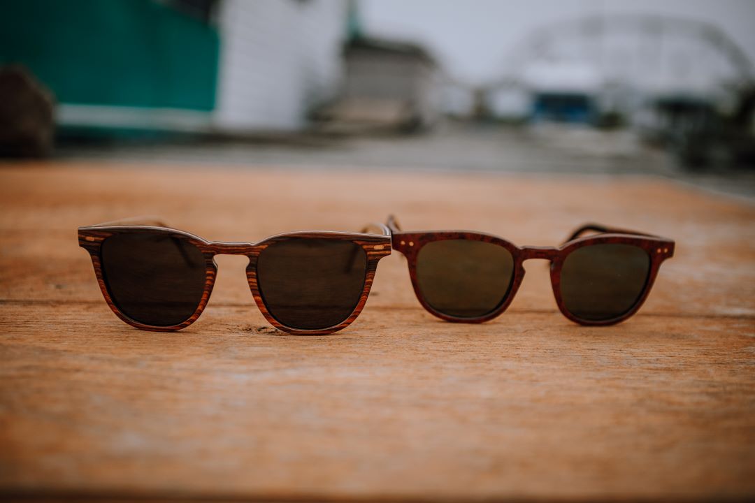 2 sunglasses sitting on wood deck. 