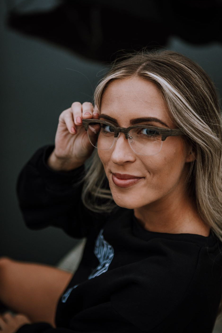 woman smiling wearing half-rim wood glasses