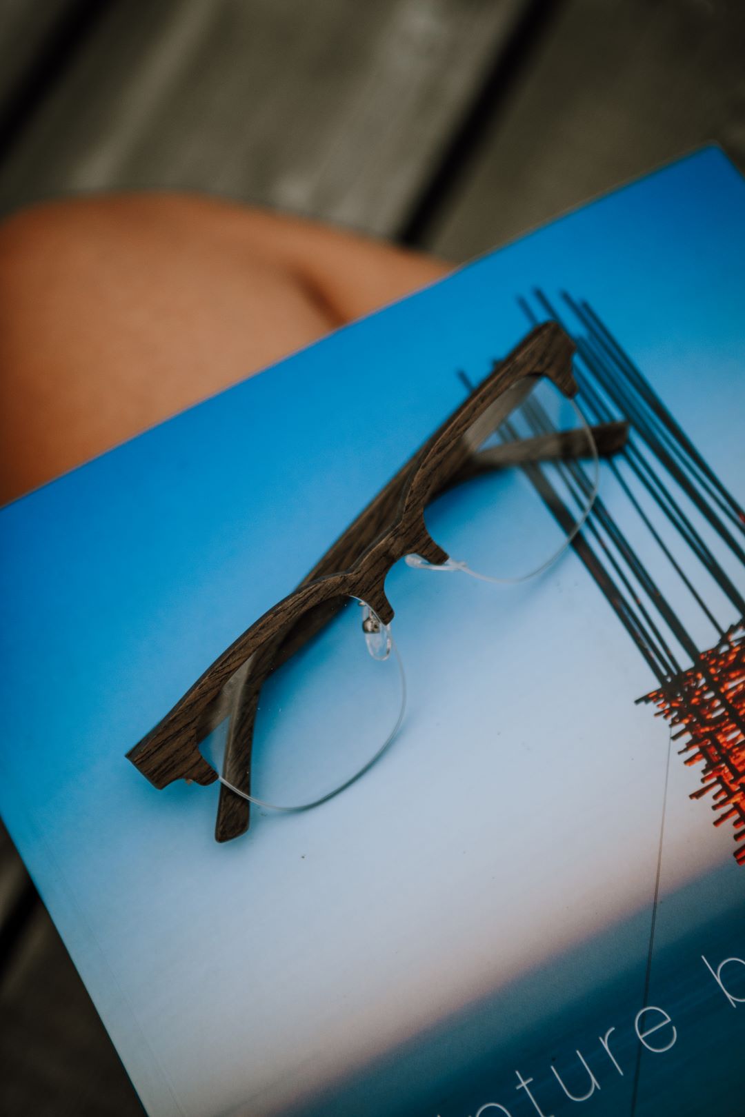 black oak eyeglasses resting on a blue book. 