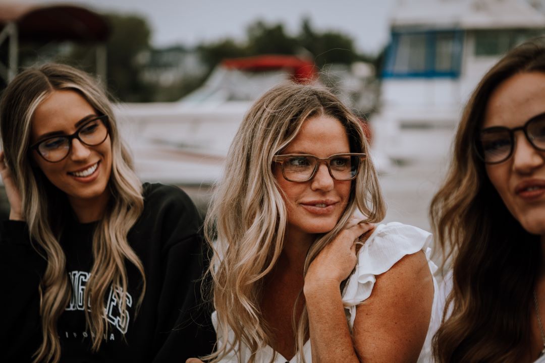 woman wearing rosewood eyeglasses, looking at friend. 